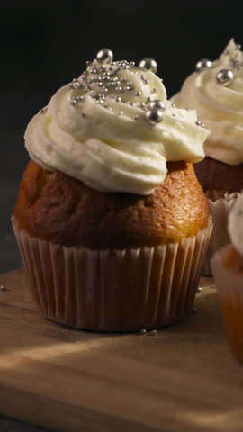 Vertical View Of Cupcakes Topped With Whipped Cream Frosting And Sprinkled With Shiny Pearl Candy. Tracking Shot