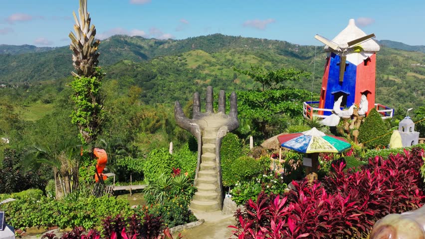 Drone glides forward to concrete hand staircase, windmill Cebu City Philippines