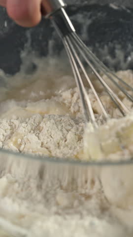 Vertical View Of A Flour Mix With Eggs Using A Whisk. Close-up Shot
