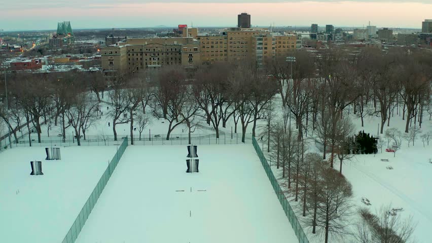drone flying over lake in park lafointaine montreal winter overlooking courts notre dame hospital n main building in the middle of the parc.