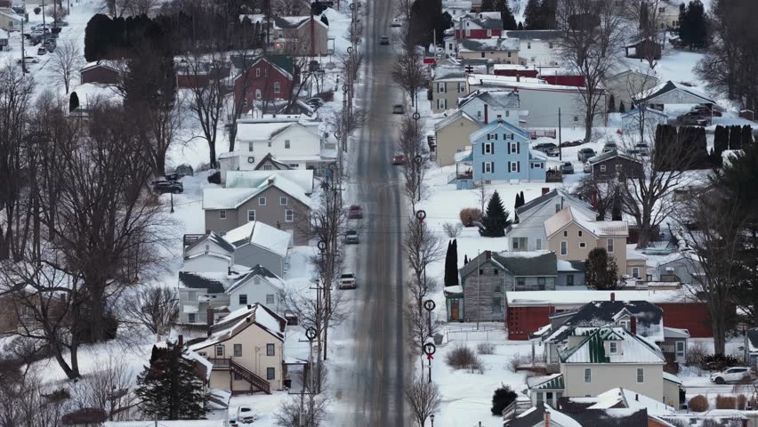 Aerial view of quiet American small town main street after fresh snowfall. Snow covered rooftops and sidewalks line calm road. Peaceful winter atmosphere in rural USA. Loretto, Pa.