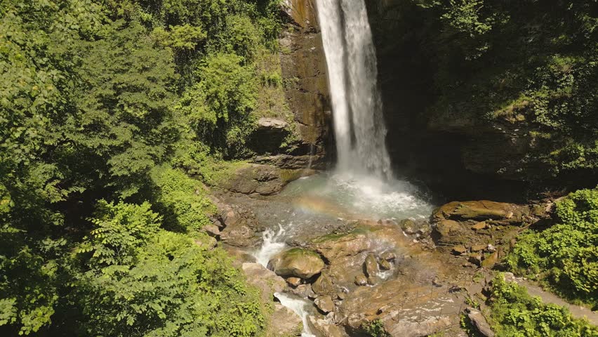Aerial view of Ninoskhevi Waterfall cascading through lush green forest into a rocky pool, located in Lagodekhi Protected Areas, Georgia