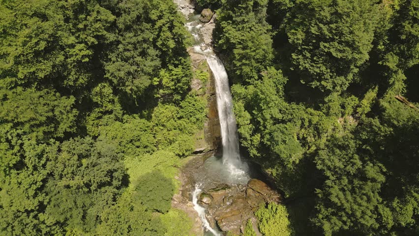Aerial view of Ninoskhevi Waterfall cascading through lush green forest into a rocky pool, located in Lagodekhi Protected Areas, Georgia