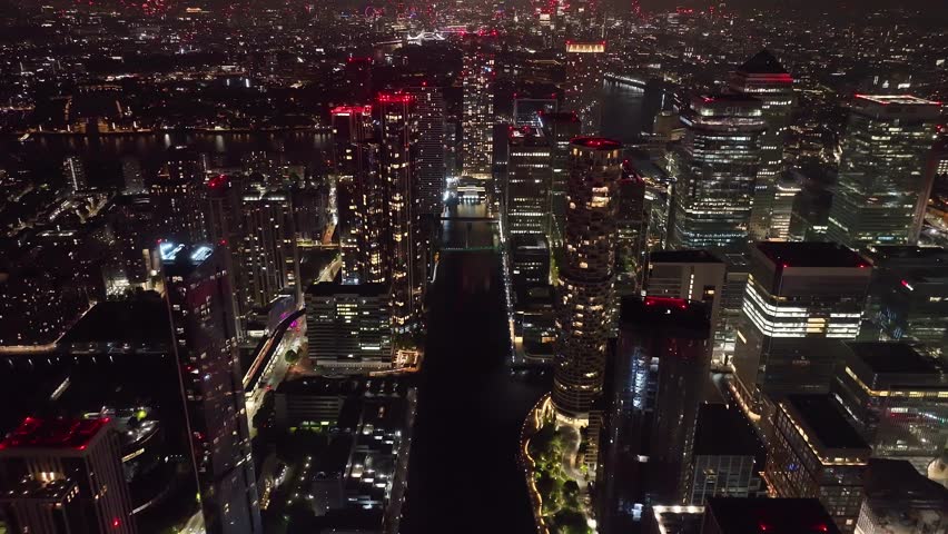 Aerial drone night cinematic video of iconic Canary Wharf skyscraper corporate complex in London, United Kingdom