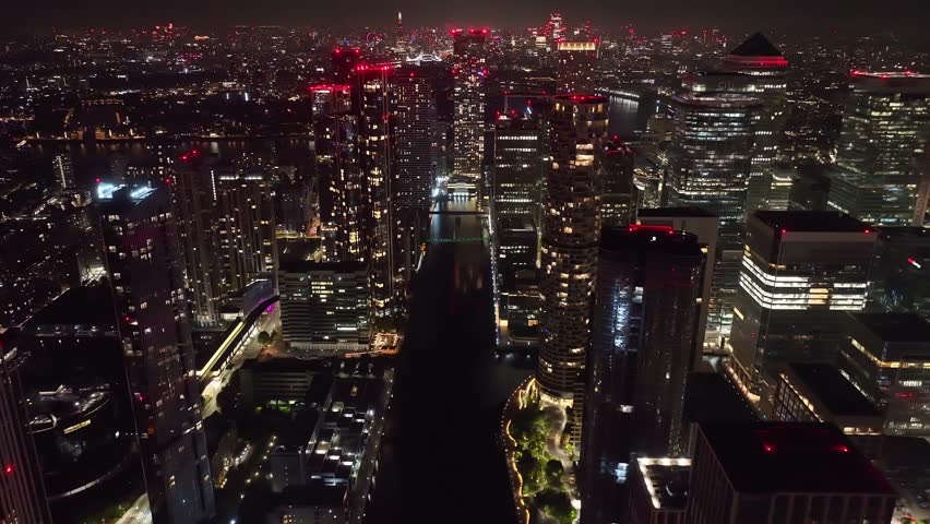 Aerial drone night timelapse night video of iconic illuminated Canary Wharf skyscraper corporate complex in London, United Kingdom