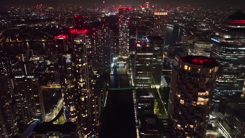 Aerial drone night cinematic video of iconic Canary Wharf skyscraper corporate complex in London, United Kingdom