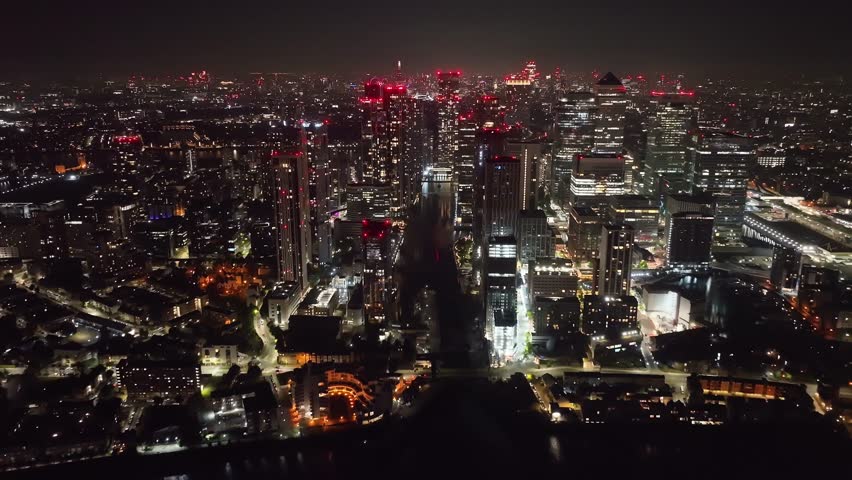 Aerial drone night cinematic video of iconic Canary Wharf skyscraper corporate complex in London, United Kingdom