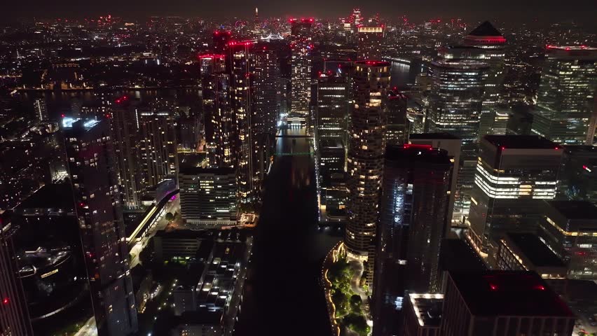 Aerial drone night cinematic video of iconic Canary Wharf skyscraper corporate complex in London, United Kingdom