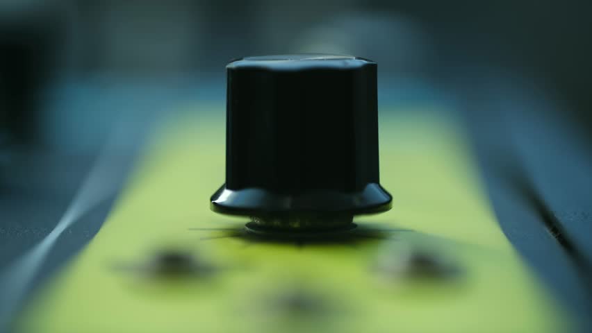 Close up person fingers turning black knob on yellow guitar amplifier or effects pedal, adjusting sound, volume, or tone settings during music session. Musician turning amplifier knob adjusting volume