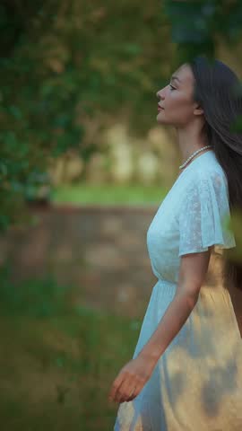 A woman in a flowing white dress moves gracefully through a dense forest, her silhouette partially obscured by vibrant green leaves and soft sunlight filtering through the canopy