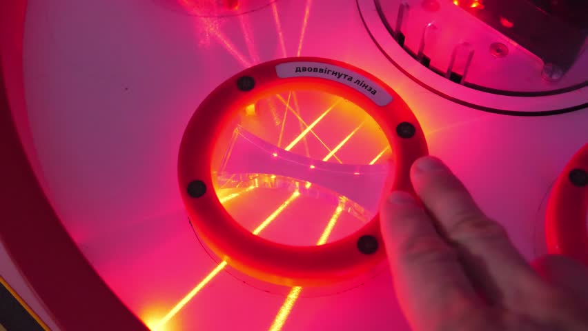 Reflection and refraction of laser beams from glass in form of biconcave lens. Hand rotates biconcave lens at different angles. Translation of the inscription from Ukrainian: biconcave lens