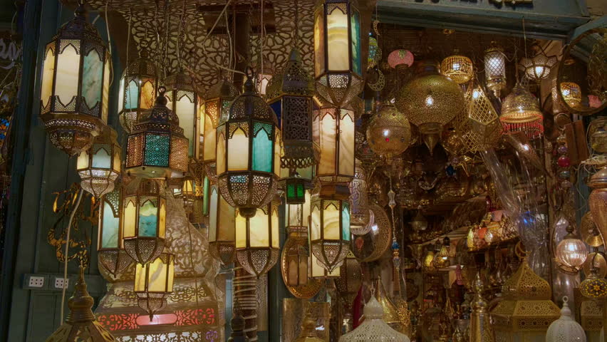 Glowing arabic lamps for sale swinging in the wind in front of egyptian souvenir shop. Traditional middle eastern lanterns. Holy month of Ramadan at Khan El Khalili market, Cairo, Egypt