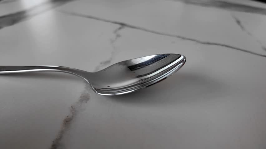 Medicine powder being poured from a sachet into a teaspoon. Healthcare and medical concept showing dosage, treatment and careful medication use. Clean background and precise action
