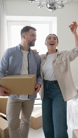 Happy couple showing keys to new home while moving in