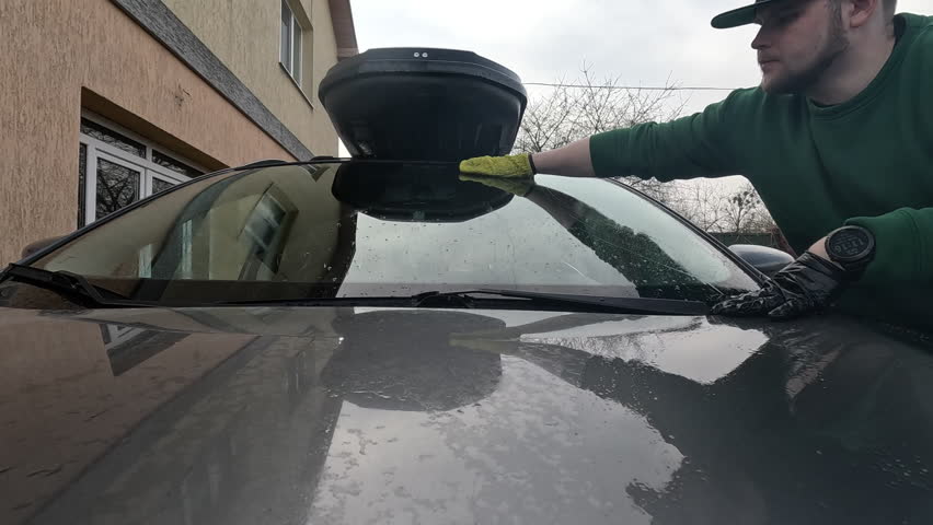Person Cleaning Car Windshield with Squeegee.