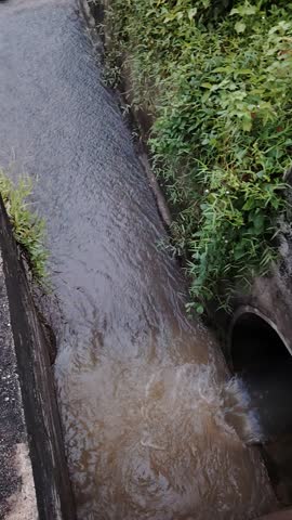 A concrete water channel with flow barriers efficiently managing turbulent water flow amidst lush green vegetation.