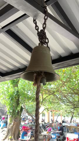 aged bronze bell suspended, It hangs from a rusty chain