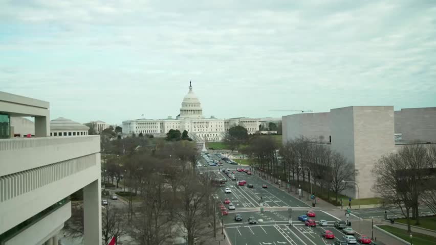 Aerial view of Washington, D.C., with traffic and the U.S. Capitol building in the background, highlighting iconic landmarks and city life.