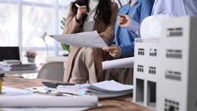 Professional engineers are examining blueprints and discussing a scale model of a building project, collaborating on design and construction plans. - Powered by Shutterstock - Get 15% off with code: PIKWIZARD15