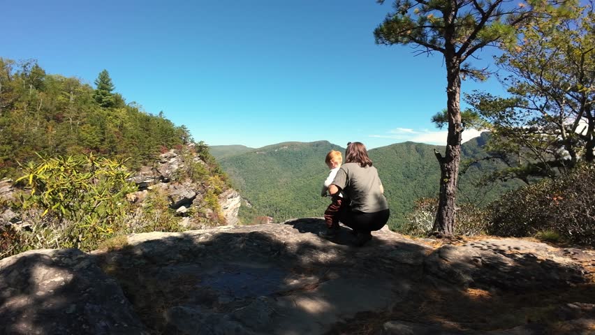 White Woman Hiker On Cliff Overlooking Mountains, Tennessee Panoramic Vista With Pine Ridges And Blue Sky, Crouched Photographing View, Rugged Rock Foreground, Distant Peaks, Crisp Autumn