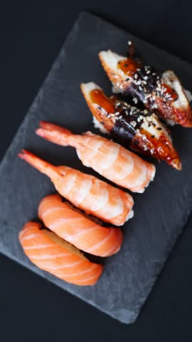 Variety of sushi is displayed on a dark tray, showing different seafood options for diners to enjoy.