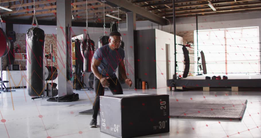 Man doing box jumps in gym, crouching initiating jump, landing stabilizing, stepping down for power. Plyometrics, strength, training, fitness, focus, conditioning, studio