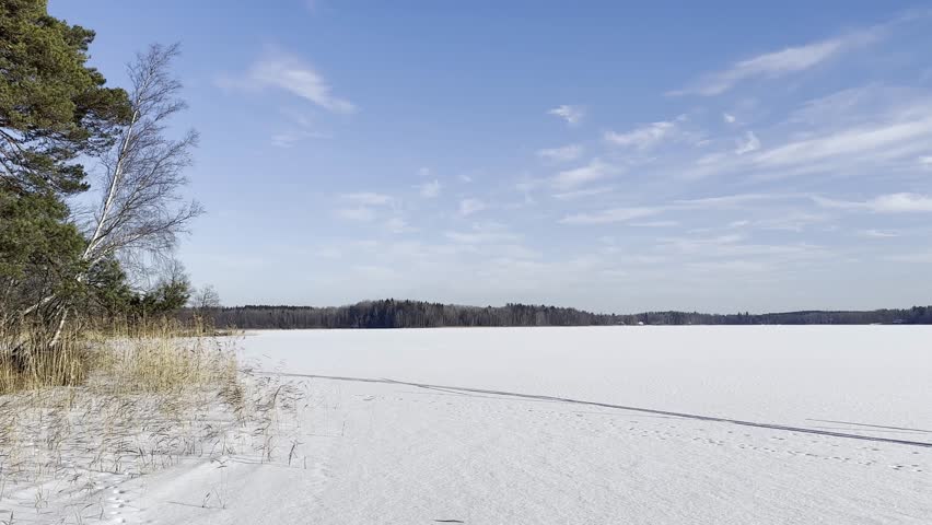 Nature and landscape video of winter in Sweden. Beautiful cold sunny day with snow and ice at the frozen lake.