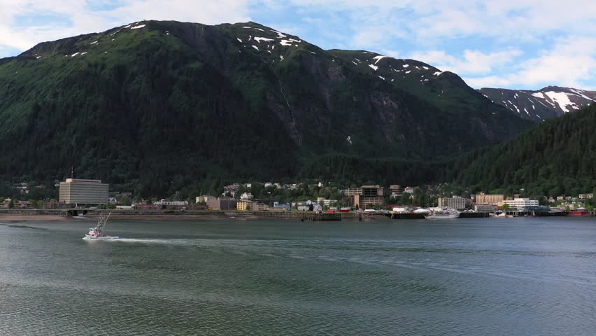 Small fishing vessel moving across the gastineau channel with the city of juneau in the background