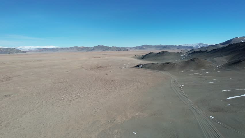Expansive Rocky Landscape. Wide Open Terrain Under Clear Sky. Largely Deserted Plain With Remote Hills And Blue Sky. Endless Arid Expanse Featuring Sparse Mountains And Unobstructed Horizon