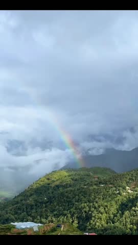 Cinematic footage of a vibrant rainbow appearing above lush green hills covered in soft mist. The natural scenery highlights fresh vegetation, atmospheric fog, and colorful light after rainfall, creating a peaceful and inspiring landscape. Ideal for travel promotions, environmental campaigns, inspirational themes, corporate backgrounds, and commercial storytelling projects.