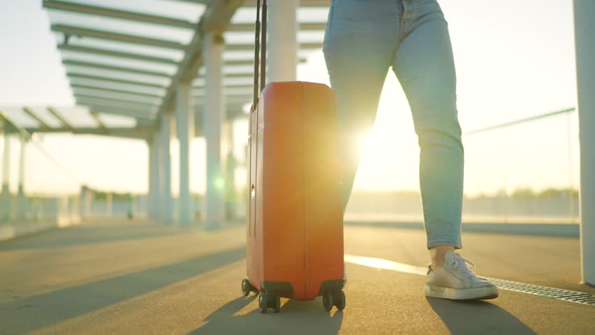 A woman confidently pulling a suitcase in an airport terminal. Slow motion