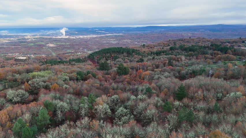 Drone flying over a beautiful autumn day with a mountain in the background. The trees are covered in leaves and the sky is cloudy in Orense, Spain.