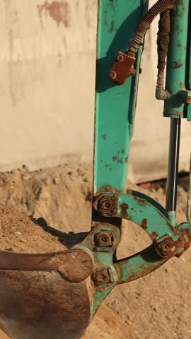 Powerful excavator bucket digging and lifting soil at active construction site. Heavy machinery in motion during earthworks and foundation preparation. Industrial equipment working on project.