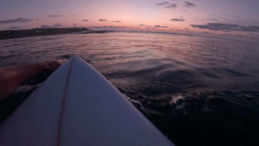 Surfer on surfboard rive on wave in ocean, first person view of surfing at sunset