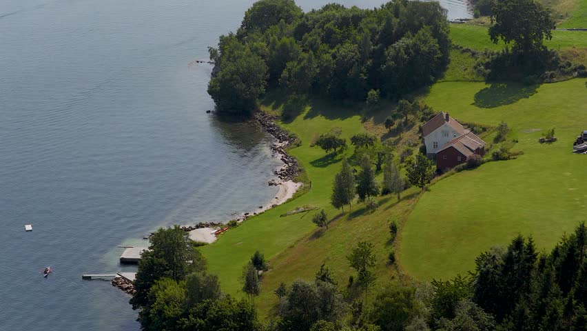 Aerial view of countryside house with private dock on peaceful lakeshore