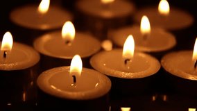Close-up of tea candles burning indoors at night against a dark background. The flame flickers and the wax cups remain stationary, creating a warm, memorable glow with a bokeh effect. - Powered by Shutterstock - Get 15% off with code: PIKWIZARD15