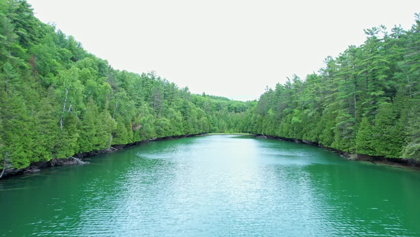 Top view of wild natural lake in Ontario, Canada, Crown land wilderness. Picturesque rocky turquoise blue lake surrounded by dense pine forests, remote dangerous routs. Epic drone view of calm water.