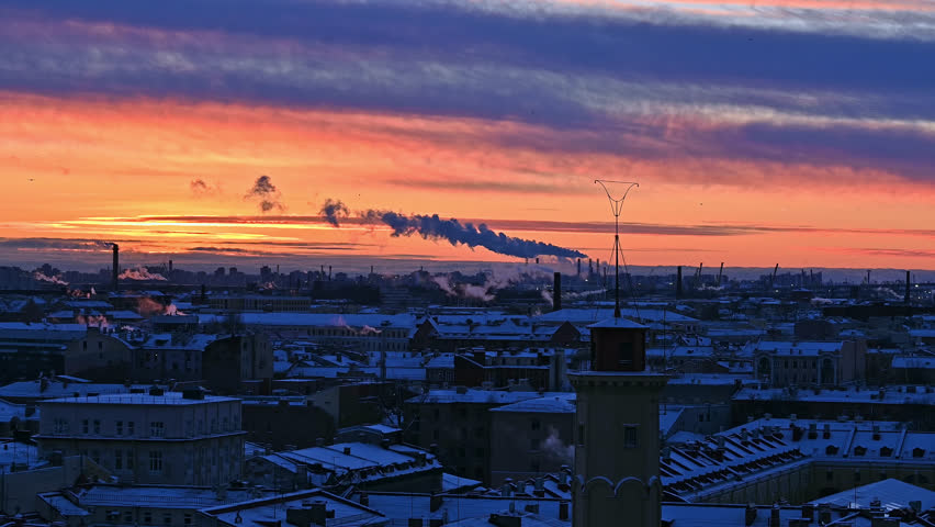 Saint-Petersburg, Russia winter cityscape - rooftop view in a sunset time. Vibrant colorful sky and blue buildings with snow on the roofs. And steam from heating utilities