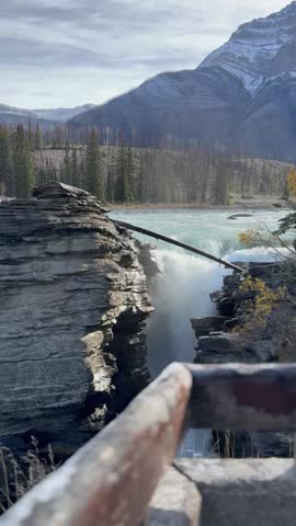 Cinematic footage of Athabasca Falls in Jasper National Park, Alberta, Canada, showcasing powerful cascading water rushing through a narrow rocky canyon. Surrounded by rugged mountain landscape and forested wilderness, the scene highlights the dramatic force and beauty of the Athabasca River as it flows through the Canadian Rockies. Ideal for travel, tourism, nature documentaries, geology, environmental storytelling, and adventure-themed content.