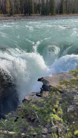 Cinematic footage of Athabasca Falls in Jasper National Park, Alberta, Canada, showcasing the powerful flow of the Athabasca River as it rushes through a dramatic rocky canyon. Surrounded by the rugged beauty of the Canadian Rockies, the scene highlights rushing glacial waters, limestone formations, and pristine wilderness, making it ideal for travel, tourism, and nature-focused projects.