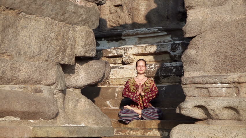 Woman doing meditation in lotus pose in Shore temple, Mamallapuram, Tamil Nadu, India
