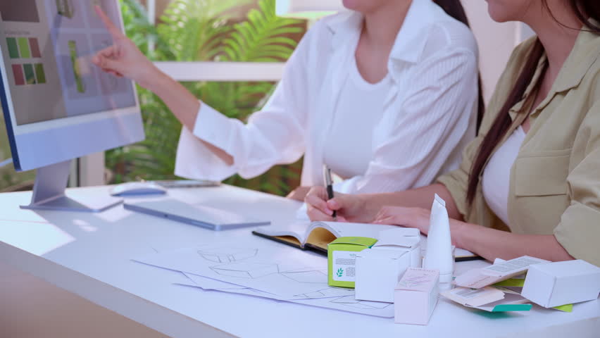 Two asian woman designer using AI artificial intelligence assistant for cosmetic packaging design development, team business marketing planning creative, product design project with AI for idea.