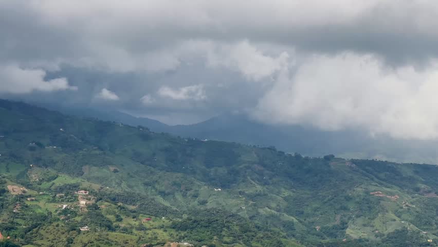 Cloudy panoramic view of Cocorná town at start, shifting to mountains with heavy rain clouds in rural Colombia