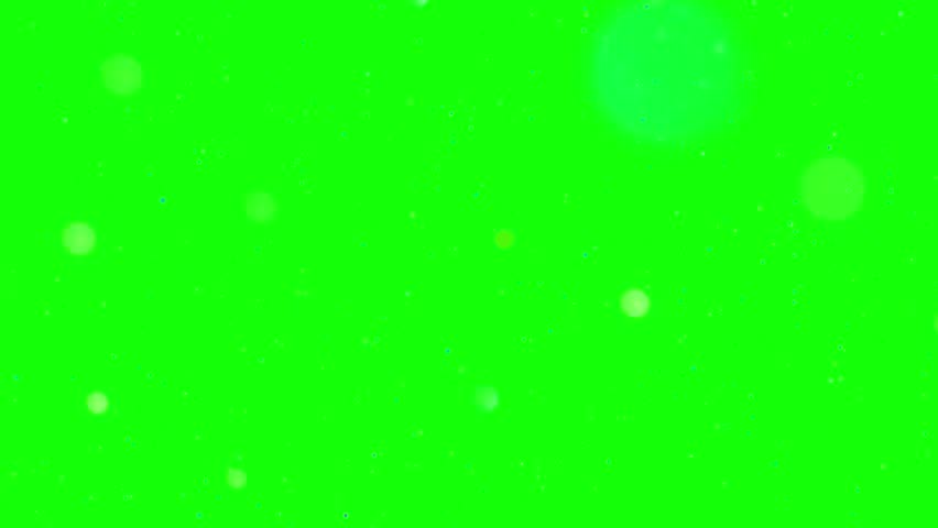 Abstract motion graphic depicts glowing ethereal spheres and tiny specks drifting slowly against a solid bright green chroma key background perfect for overlaying science or fantasy visual effects in video production.
