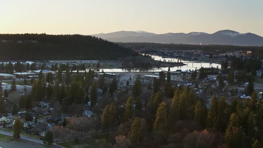 Aerial view of Coeur d’Alene, Idaho, showcasing the city, sparkling lake, and majestic mountains in the scenic background.