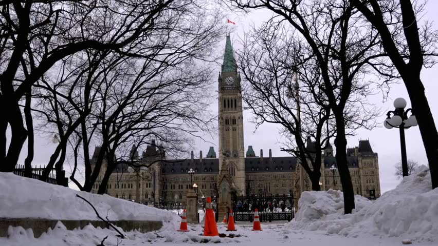 Parliament Hill in Ottawa, Canada during winter, with snow-covered grounds and bare trees, showcasing iconic government buildings in a serene seasonal setting.