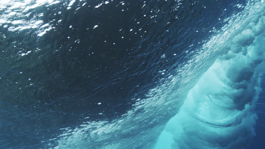 Powerful underwater wave face curling with bright turquoise light and textured motion