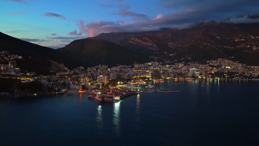 Aerial drone view of a Budva illuminated by scattered building and street lights at night. Montenegro