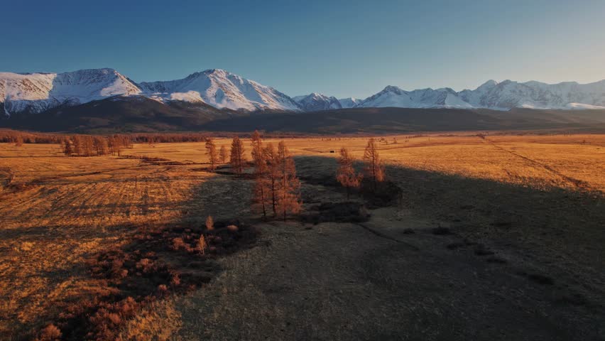Aerial view Altai Russia, beautiful landscape autumn forest meandering road with snow peaks mountains.