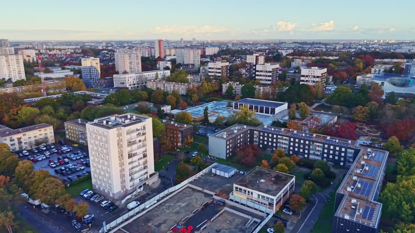 Jean Normand square, the conservatory, and residential buildings in the Le Blosne district during a golden sunrise in Rennes, France. Aerial drone panoramic view